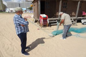 Fishermen knotting nets in Armacao de Pera. Large sandy flat beaches. Dogs allowed